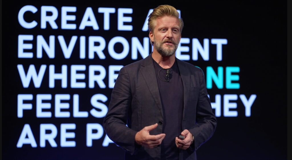 A speaker emphasizes the importance of fostering an environment where everyone feels included and valued, with a focus on engagement and belonging.